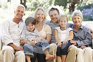 Three Generation Family Sitting On Sofa At Home