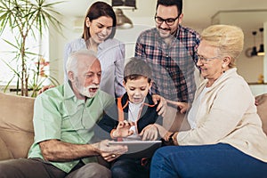 Three generation family spending time together at home using digital tablet