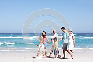 Three Generation Family Walking Along Sandy Beach