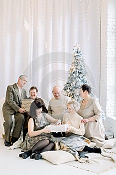 A Three Generation Happy Family at Christmas. Smiling family at christmas swapping gifts, sitting on the floor in cozy
