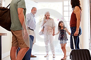 Three generation white family at front door preparing to leave home to go on holiday, close up, crop