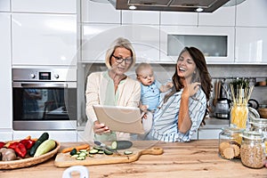 Three Generations Family. Grandma, mother and baby record a cooking vlog or podcast while chopping vegetables for a healthy