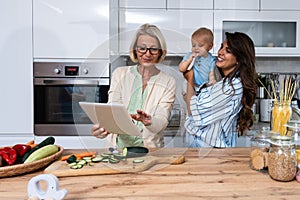 Three Generations Family. Grandma, mother and baby record a cooking vlog or podcast while chopping vegetables for a healthy