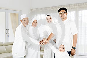 Three generations family joining hands at home