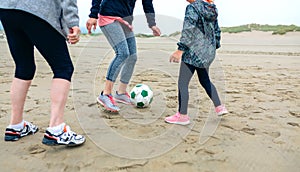 Three generations female playing soccer on the beach