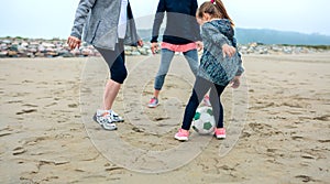 Three generations female playing soccer on the beach