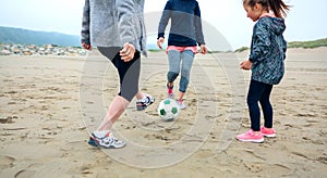 Three generations female playing soccer on the beach