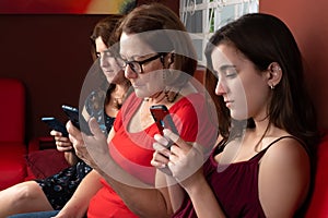 Three generations of hispanic women looking at their smartphones