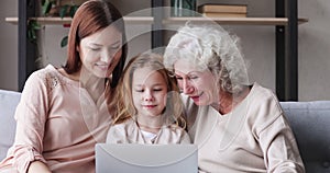 Three generations women family laughing watching funny videos on laptop