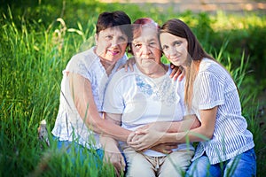 Three generations of women - the grandmother, mother and the daughter. A family portrait in greens outdoors