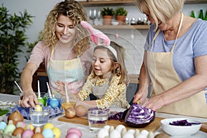 Three generations of women making Easter eggs