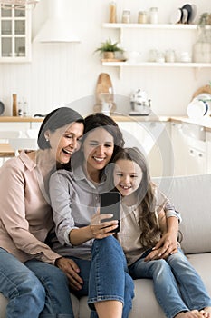 Three generations of women rest on couch with cellphone