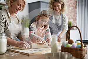 Three generations of women rolling dough
