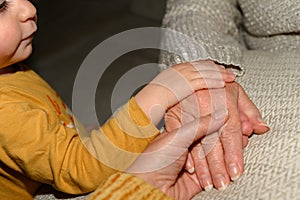 Three generations of women touch each other with their hands: a girl, a mature woman and a senior woman. Concept of affection and