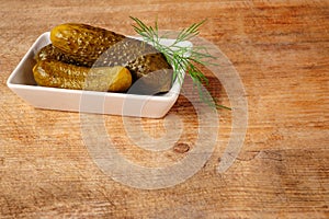 Three gherkins in bowl over wood