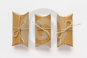 Three gifts made of craft paper wrapped with packthread