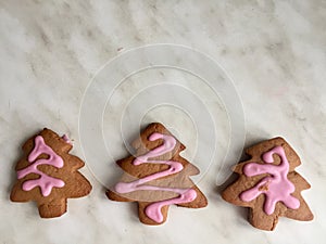 three ginger herringbone-shaped cookies, with pink icing sugar, grey background. ginger biscuits in herringbone form with pink