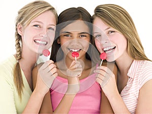 Three girl friends with suckers smiling