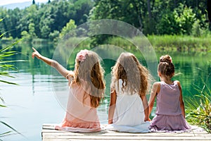 Three girl friends together on river jetty.