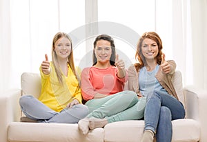 Three girlfriends showing thumbs up at home