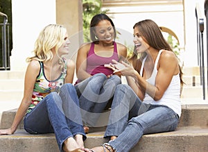 Three Girlfriends Sitting On Steps Of Building photo