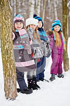 Three girls and boy stand in winter park