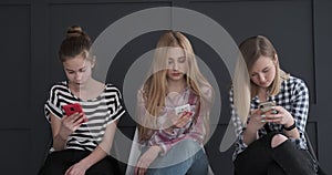 Three girls chatting using their mobile phones