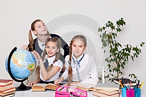 Three girls in the classroom studying geography globe of planet Earth