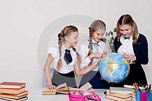 Three girls in the classroom studying geography globe of planet Earth