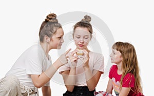 Three girls eating doughnut and smiling, Studio portrait on white background