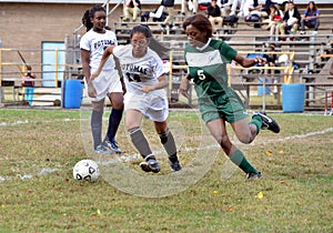 Three girls playing a girls` high school soccer game