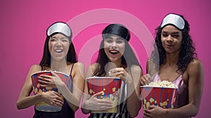 Three girls with eye masks eating popcorn and laughing out loud, funny comedy