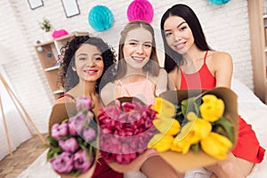 Three girls with flowers. They are celebrating women`s day March 8.