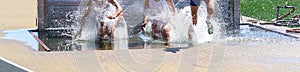 Three girls getting very wet in the water pit of the steeplechase during a track race