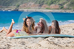 Three girls having fun on a beach with surboard