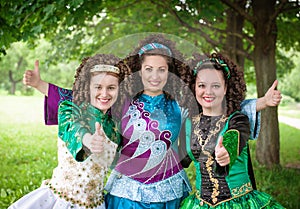 Three girls in irish dance dresses showing thumbs up