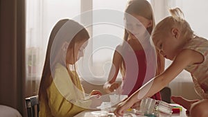 Three girls mixing ingredients together to make slime. Family, hobbies