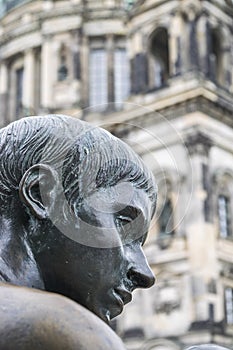 Three Girls One Boy Statue, detail of the boy`s face with the cathedral in the background