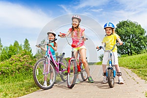 Three girls on a pave road with bicycles photo