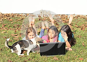 Three girls playing with notebook and dog
