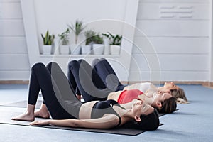 Three girls practicing yoga. Yoga instructor with her students meditating in a studio