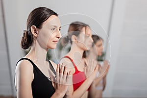 Three girls practicing yoga. Yoga instructor with her students meditating in a studio