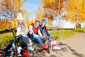 Three girls putting on roller blades in the park