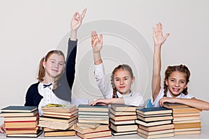 Three girls raise their hand up in school class