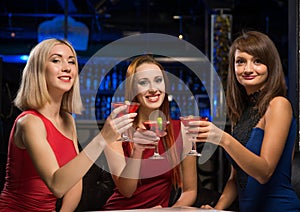 Three girls raised their glasses in a nightclub