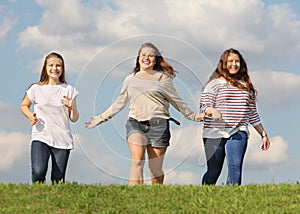 Three girls run at grass and smile