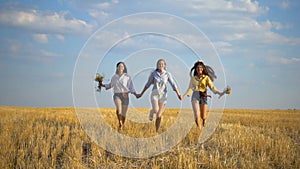 Three girls running on stubble field, slow motion