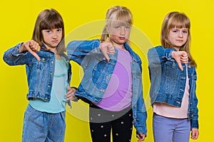 Three girls siblings friends showing thumbs down sign gesture, disapproval, dissatisfied, dislike