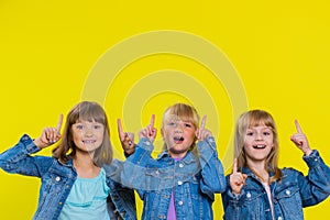 Three girls siblings friends showing thumbs up and pointing empty place, advertising promotion area