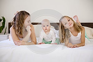 Three girls sisters in the morning in the bedroom on the bed play